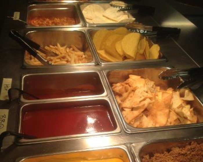 The taco and wing buffet line: wings, soft tortillas, seasoned beef, fries, tortilla chips, sauces and nacho cheese in steam-table pans.