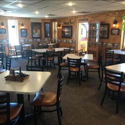 The dining room: knotty pine walls, framed prints, a longhorn skull mounted above the wainscot and a doorway signed Tack Shop.