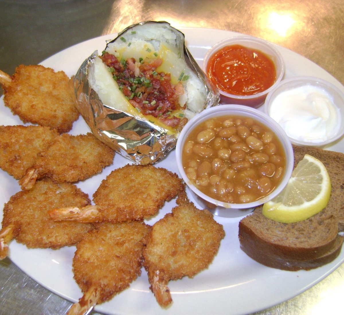 Seven jumbo fantail shrimp with a loaded baked potato, baked beans, cocktail sauce, sour cream, lemon and rye bread.